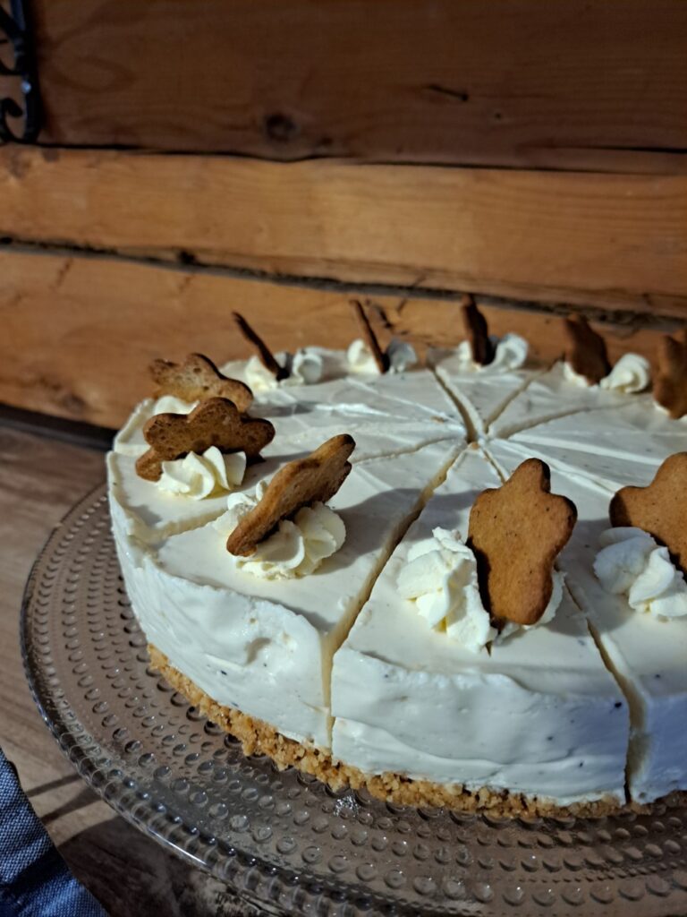 Valkoinen juustokakku joka on koristeltu pienillä pipareilla